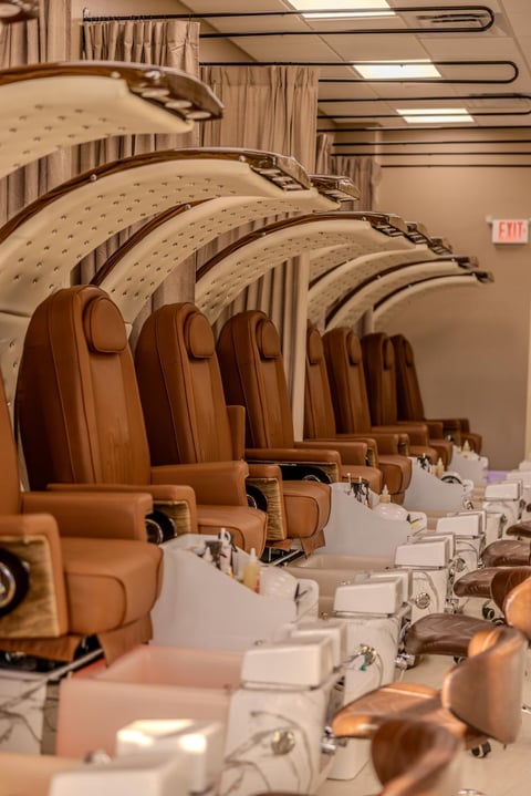 Row of tan leather airplane seats with white tray tables in aircraft cabin with curved interior design
